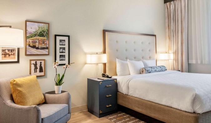 A shinning inn room with craftsmanship on the dividers, an simple chair, and a ruler measured bed at St. Charles Coach House, a inn in Unused Orleans, Louisiana