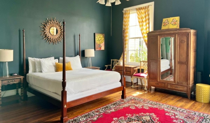 A visitor room with profound green dividers, hardwood floors, a four-poster bed, wooden closet, and huge windows at Creole Gardens Motel, a inn in Unused Orleans, Louisiana